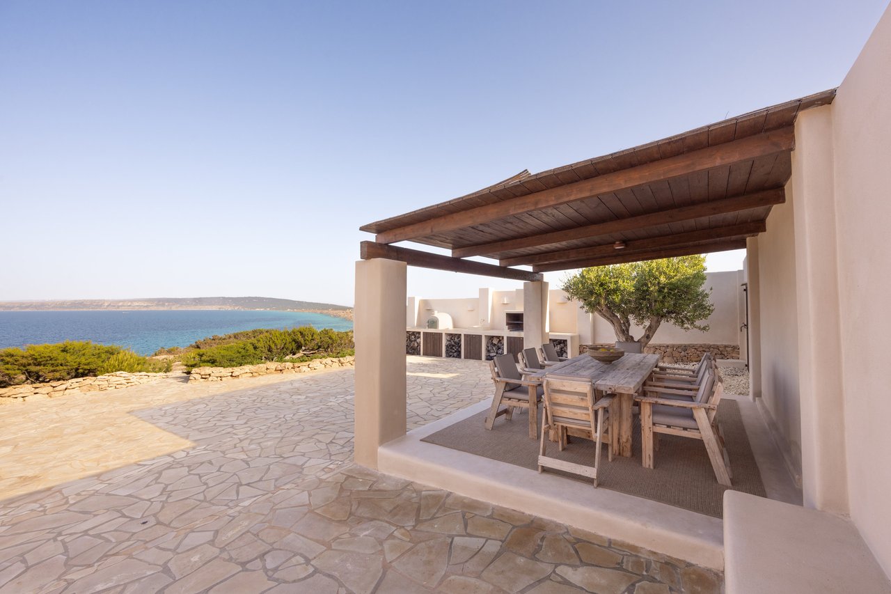 Pérgola de madera con la mesa exterior, el olivo y el mar