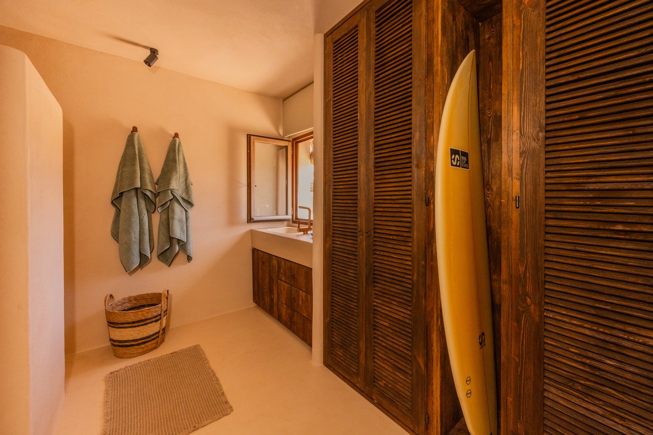 Baño de la habitación 04 con armarios de lamas y tabla de surf